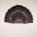 Kabash Outdoors American steel turkey fan display hanger. Fan holder is rustic brown and looks like the end of a 12ga shotgun shell. It is holding a beautiful turkey tail.