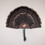 Kabash Outdoors American steel turkey fan display hanger. Fan holder is rustic brown with a turkey silhouette cutout. It is holding a beautiful turkey tail and beard.